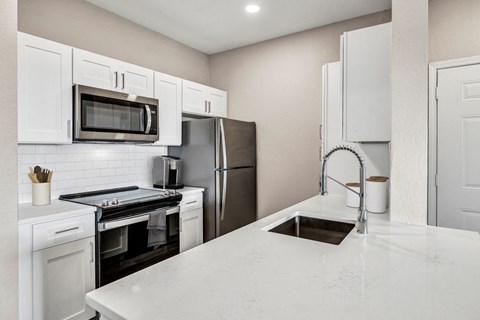 a kitchen with white cabinets and stainless steel appliances